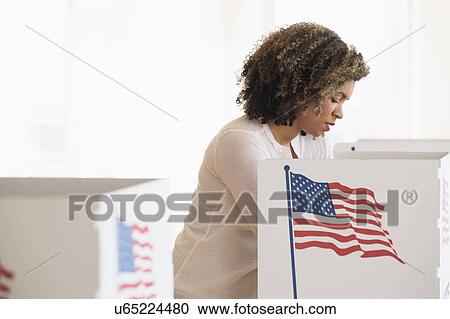 Stock Image - Young woman preparing voting booth. Fotosearch