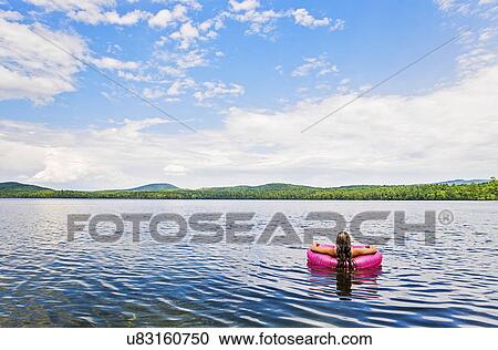 Stock Image - Young woman relaxing on lake in pool raft. Fotosearch