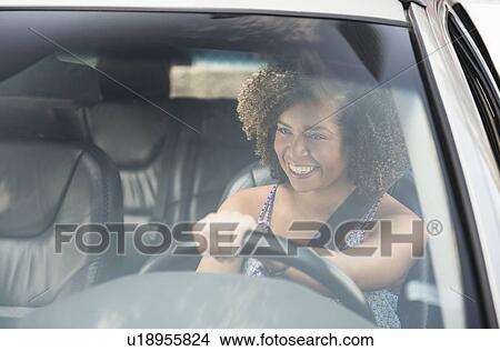 Young woman smiling while driving car View Large Photo Image Picture - Young woman smiling while driving car. Fotosearch