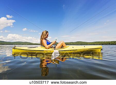 Young woman using Smartphone in kayak on lake View Large Photo Image Stock Photo - Young woman using Smartphone in kayak on lake. Fotosearch