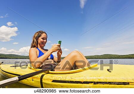 Young woman using Smartphone in kayak on lake View Large Photo Image Stock Photography - Young woman using Smartphone in kayak on lake. Fotosearch