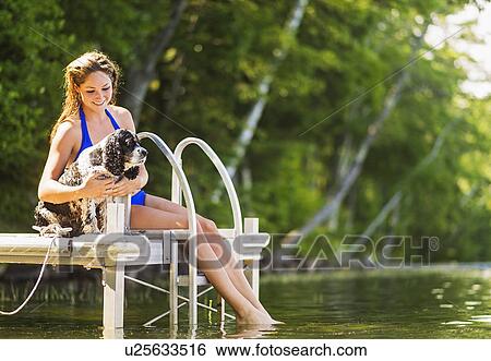 Young woman with dog sitting on jetty over lake View Large Photo Image Stock Photograph - Young woman with dog sitting on jetty over lake. Fotosearch