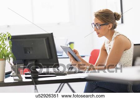 Stock Image - Young woman working in office. Fotosearch
