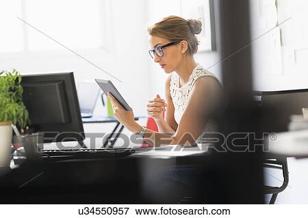 Stock Photo - Young woman working in office. Fotosearch