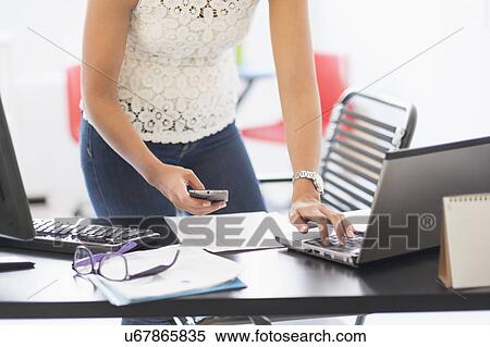 Stock Photography - Young woman working in office. Fotosearch