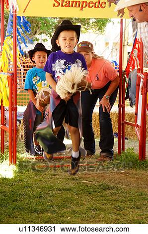 Stock Image -  boy riding stick bull at the pee-wee stampede. Fotosearch