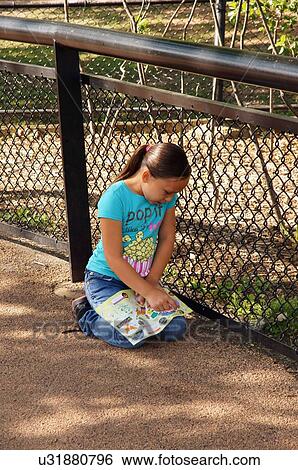 Stock Photograph -  girl child kid female alone read lonely como zoo. Fotosearch