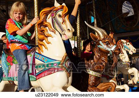 Stock Photo -  girl girls child kid on carousel horse amusement. Fotosearch