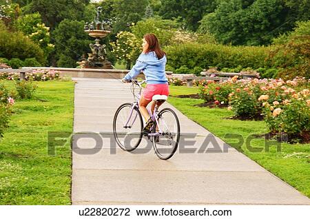 Stock Image -  girl riding bicycle in lake harriet rose garden. Fotosearch