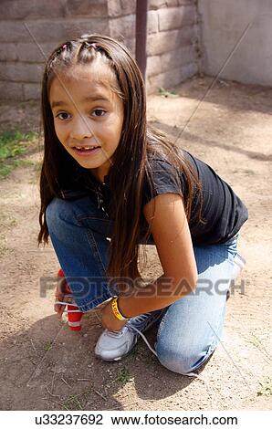 Stock Image -  little latino hispanic girl child kid tying her. Fotosearch
