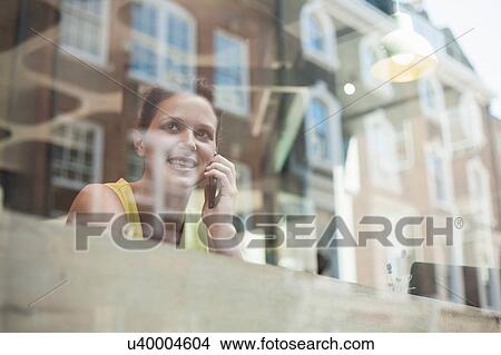 A young brunette woman sitting in a cafe using mobile phone View Large Photo Image Picture - A young brunette woman sitting in a cafe using mobile phone. Fotosearch