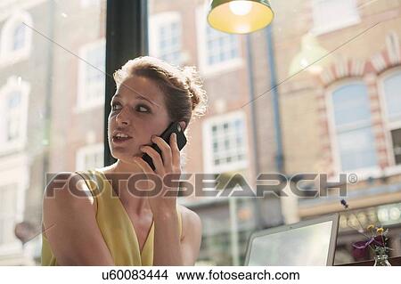 A young brunette woman sitting in a cafe using mobile phone View Large Photo Image Picture - A young brunette woman sitting in a cafe using mobile phone. Fotosearch