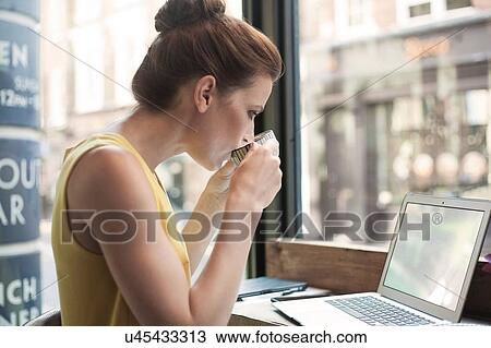 A young brunette woman sitting in a cafe working View Large Photo Image Stock Image - A young brunette woman sitting in a cafe working. Fotosearch