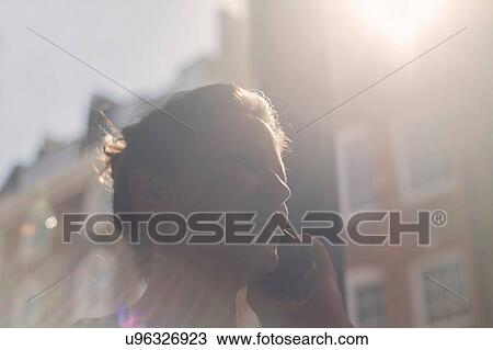 Stock Image - A young brunette woman sitting in a cafe using mobile phone. Fotosearch