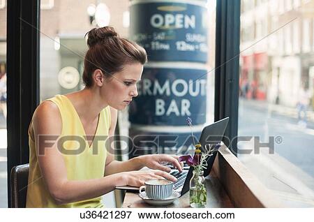 A young brunette woman sitting in a cafe working View Large Photo Image Stock Photo - A young brunette woman sitting in a cafe working. Fotosearch