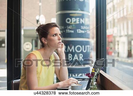 A young brunette woman sitting in a cafe working View Large Photo Image Stock Photo - A young brunette woman sitting in a cafe working. Fotosearch