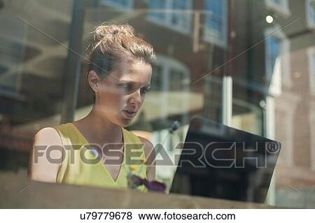 A young brunette woman sitting in a cafe working View Large Photo Image Stock Photo - A young brunette woman sitting in a cafe working. Fotosearch