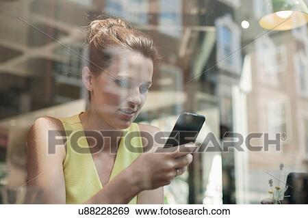 A young brunette woman sitting in a cafe using mobile phone View Large Photo Image Stock Photo - A young brunette woman sitting in a cafe using mobile phone. Fotosearch