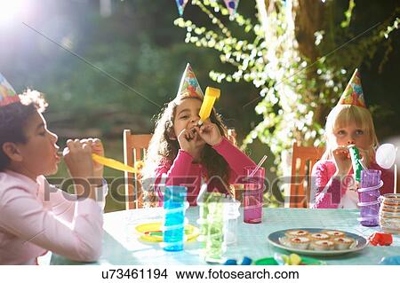 Boy and girls blowing party horns at garden birthday party View Large Photo Image Picture - Boy and girls blowing party horns at garden birthday party. Fotosearch