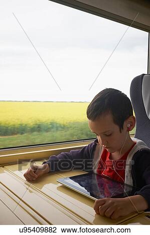 Boy on train reading digital tablet View Large Photo Image Stock Image - Boy on train reading digital tablet. Fotosearch