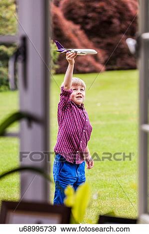 Boy playing in garden with toy airplane View Large Photo Image Stock Photo - Boy playing in garden with toy airplane. Fotosearch