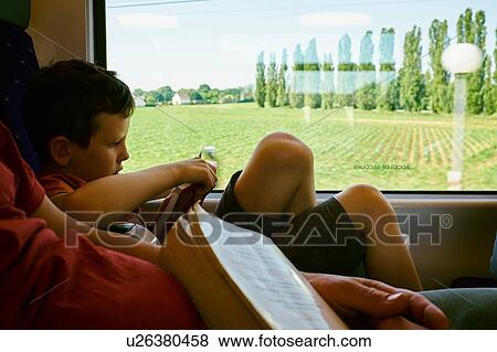 Stock Photo - Boy reading book next to train carriage window. Fotosearch