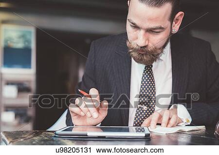 Businessman making diary notes from digital tablet at cafe table View Large Photo Image Stock Image - Businessman making diary notes from digital tablet at cafe table. Fotosearch