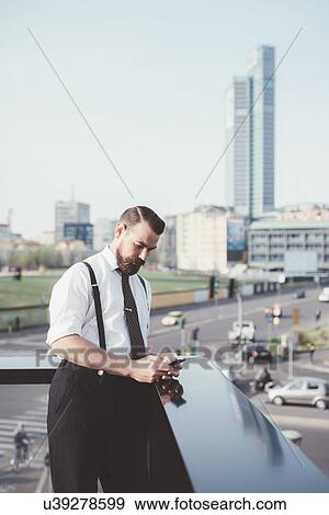 Businessman reading smartphone text update on office balcony View Large Photo Image Stock Photo - Businessman reading smartphone text update on office balcony. Fotosearch