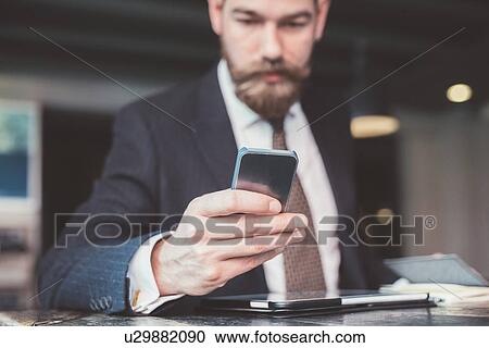 Businessman reading smartphone update at cafe table View Large Photo Image Stock Image - Businessman reading smartphone update at cafe table. Fotosearch