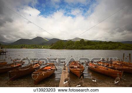 Stock Image - Canoes by lake edge, Lake District, Cumbria, UK. Fotosearch