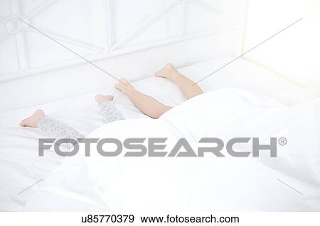 Children's feet sticking out of bed playing hiding under the bedsheets View Large Photo Image Stock Photo - Children's feet sticking out of bed playing hiding under the bedsheets. Fotosearch