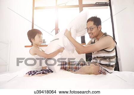 Picture - Chinese father and son having a pillow fight. Fotosearch