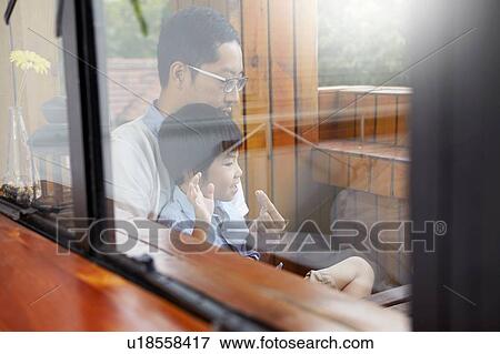 Chinese father and young son having breakfast on the balcony in the sunshine together, shot through window View Large Photo Image Stock Photo - Chinese father and young son having breakfast on the balcony in the sunshine together, shot through window. Fotosearch