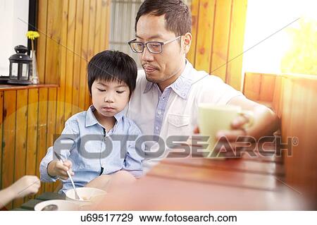 Chinese father and young son having breakfast on the balcony in the sunshine together View Large Photo Image Stock Photo - Chinese father and young son having breakfast on the balcony in the sunshine together. Fotosearch