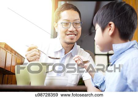 Stock Photo - Chinese father and young son having breakfast on the balcony in the sunshine together. Fotosearch