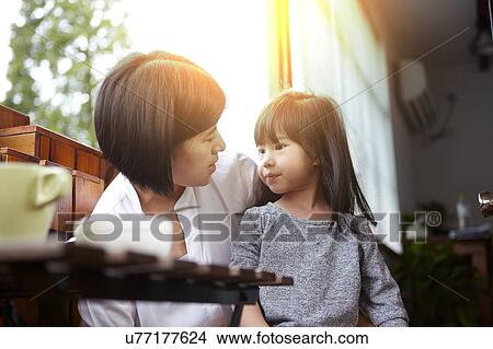 Chinese mother and young daughter having breakfast on the balcony in the sunshine together View Large Photo Image Picture - Chinese mother and young daughter having breakfast on the balcony in the sunshine together. Fotosearch