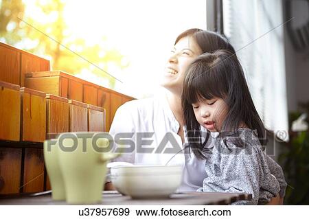 Chinese mother and young daughter having breakfast on the balcony in the sunshine together View Large Photo Image Stock Photo - Chinese mother and young daughter having breakfast on the balcony in the sunshine together. Fotosearch