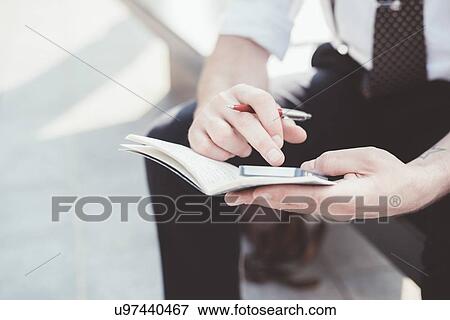 Close up of businessman making diary notes from smartphone on city seat View Large Photo Image Stock Photo - Close up of businessman making diary notes from smartphone on city seat. Fotosearch