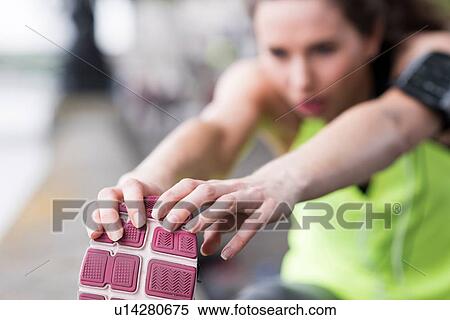 Stock Photography - Close up of female runner touching toes. Fotosearch