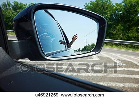 Stock Photo - Close up of mother photographing sons hand reflected in wing mirror. Fotosearch