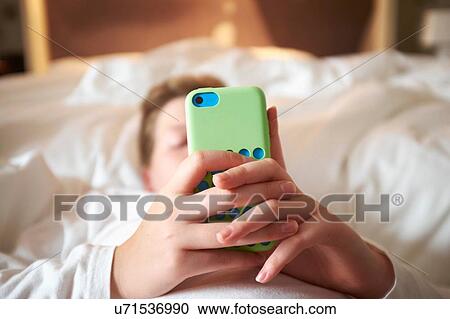 Close up of teenage boys hands holding smartphone on bed View Large Photo Image Stock Image - Close up of teenage boys hands holding smartphone on bed. Fotosearch