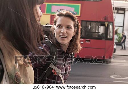 Close up of two women backpackers chatting whilst strolling on city sidewalk View Large Photo Image Picture - Close up of two women backpackers chatting whilst strolling on city sidewalk. Fotosearch