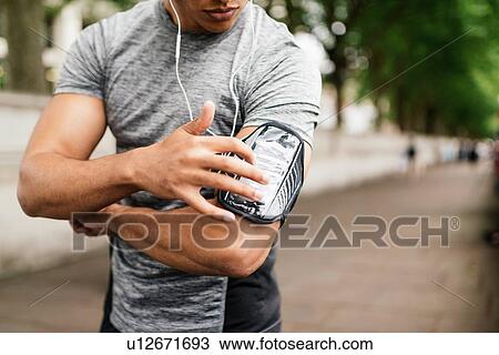 Cropped shot of male runner choosing music on smartphone View Large Photo Image Stock Image - Cropped shot of male runner choosing music on smartphone. Fotosearch