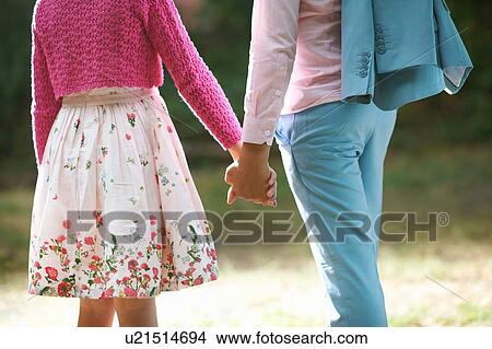 Cropped view of girl and boy holding hands in garden View Large Photo Image Picture - Cropped view of girl and boy holding hands in garden. Fotosearch