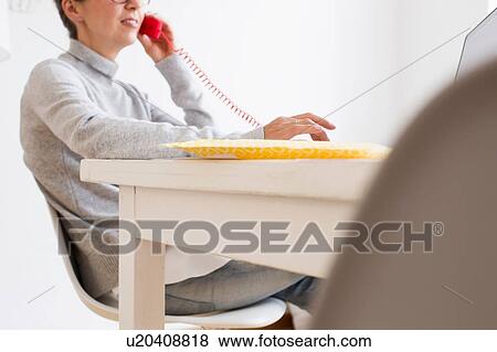Cropped view of mature woman sitting at table using landline telephone, differential focus View Large Photo Image Stock Photo - Cropped view of mature woman sitting at table using landline telephone, differential focus. Fotosearch