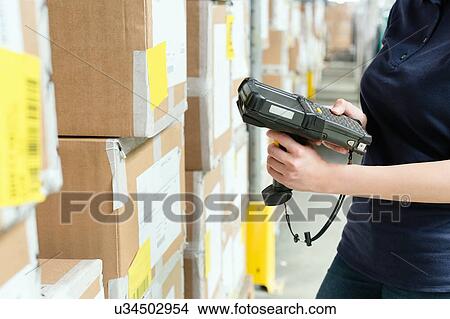 Picture - Cropped view of warehouse worker using barcode scanner on box in distribution warehouse. Fotosearch