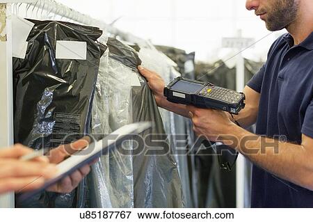 Stock Photo - Cropped view of warehouse workers using barcode scanner on garment stock in distribution warehouse. Fotosearch