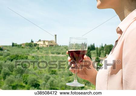 Cropped view of young woman holding wine glass looking away View Large Photo Image Stock Image - Cropped view of young woman holding wine glass looking away. Fotosearch
