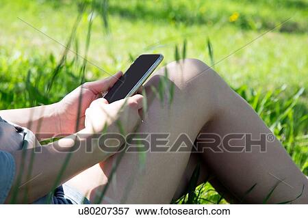 Stock Photo - Cropped view of young woman using smartphone. Fotosearch