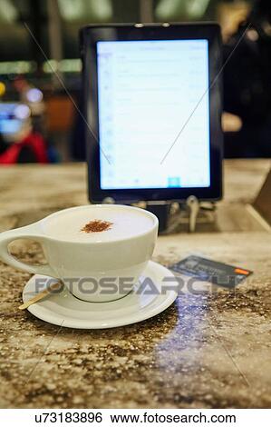 Cup of coffee, digital tablet and credit card on restaurant table View Large Photo Image Stock Photograph - Cup of coffee, digital tablet and credit card on restaurant table. Fotosearch